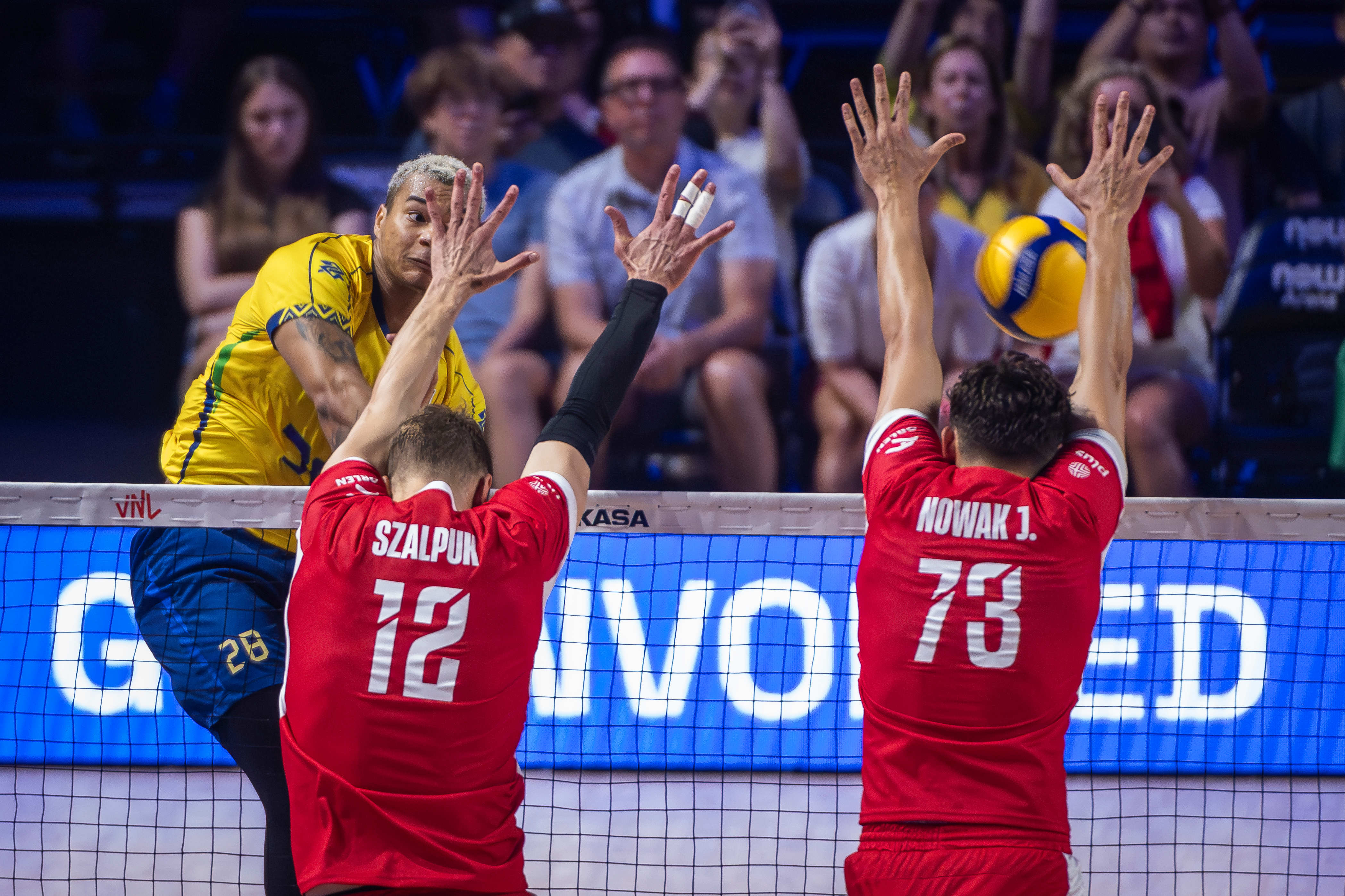 Brazil’s Darlan Souza spikes against the block of Poland’s Artur Szalpuk and Jakub Nowak