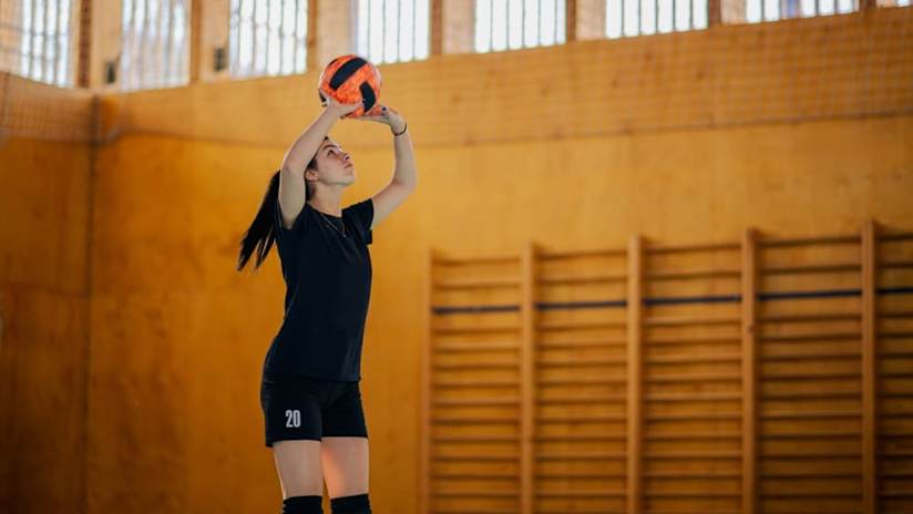 A volleyball player is setting a ball on the court during training