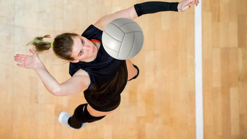 A woman demonstrates how to jump serve.