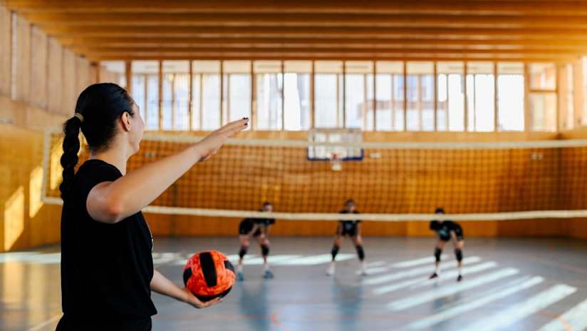 A player prepares to serve on an indoor court.