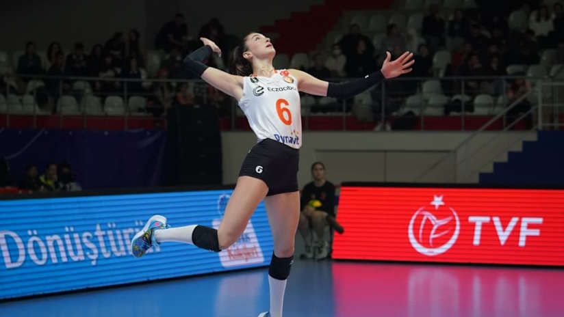 A female volleyball player doing a jump serve