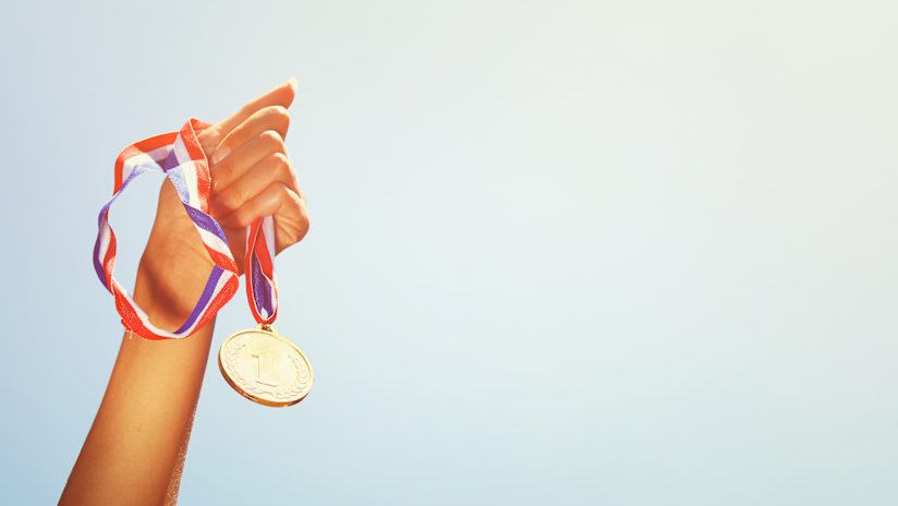 A woman holding up a winning medal