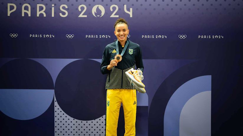 Gabi poses with her bronze medal and the signed shoes she parted with for the Olympic heritage cause