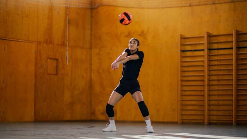 A woman demonstrates the proper volleyball passing technique.