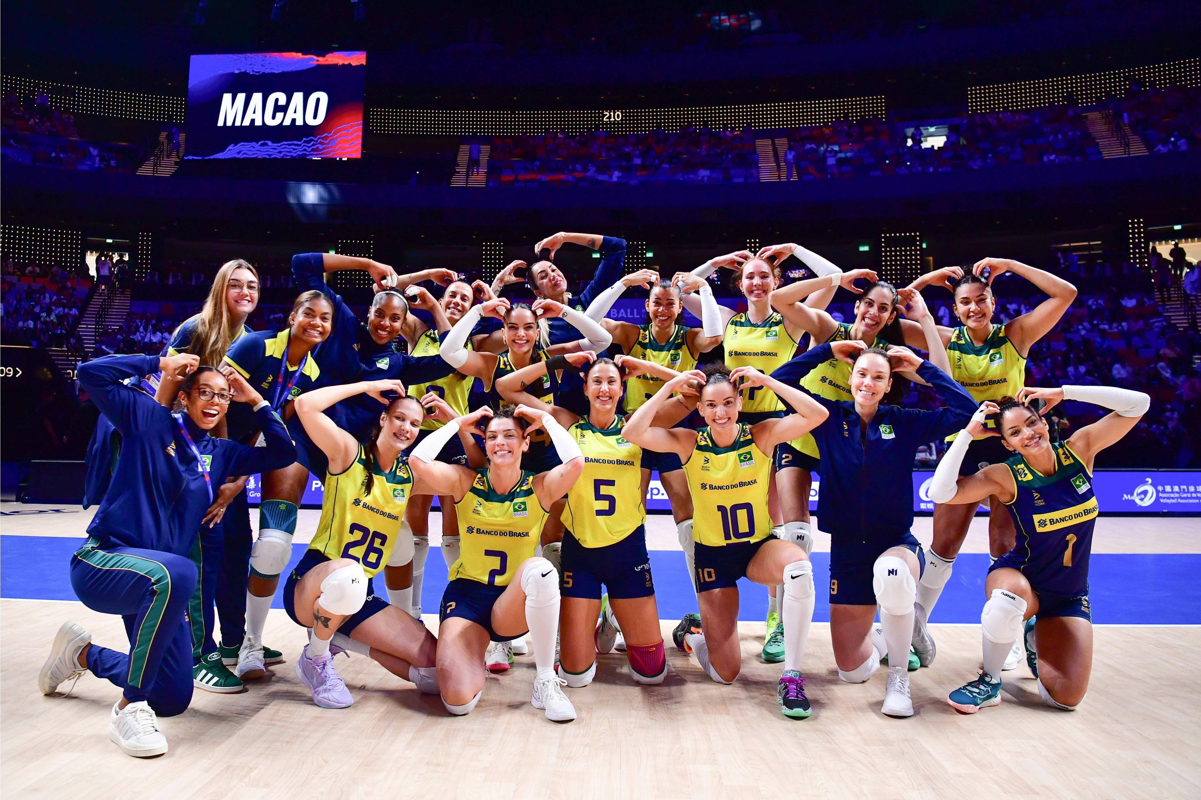 De amarelo, seleção posa para foto com as jogadoras colocando as duas mãos na cabeça